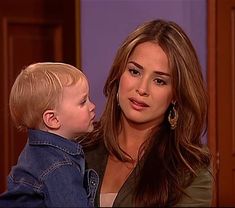 a woman holding a young boy in her lap and looking at him with an intense look on his face