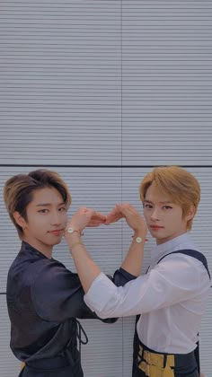 two young men standing next to each other with their hands in the shape of a heart