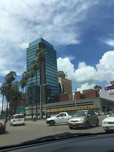 cars are driving down the street in front of tall buildings and palm trees on a sunny day