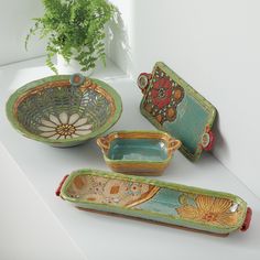 three pieces of pottery sitting on top of a white counter next to a potted plant