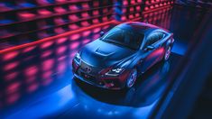 a red car driving through a tunnel with bright lights on the walls and flooring