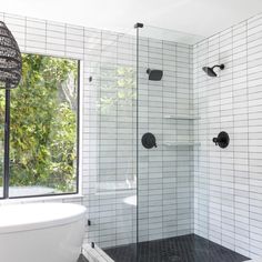 a bathroom with a glass shower door and black tile on the floor, along with a white bathtub