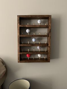 a wooden rack with several balls in it on the wall next to a bowl and chair