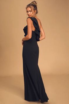 a woman in a black dress is standing with her back to the camera and looking at something