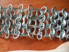 a hand holding a metal chain on top of a wooden table