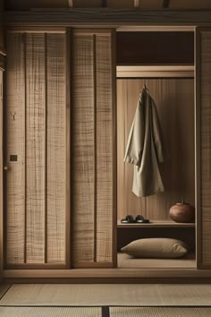 an open wooden closet with clothes hanging on the door and shoes in the room next to it