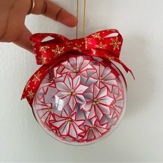 a hand holding a red ornament with gold decorations on it's side