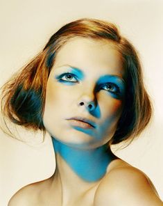 a woman with blue makeup is posing for the camera