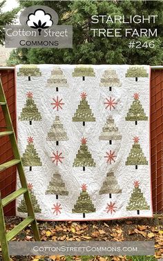 a quilted christmas tree is hanging on a fence next to a ladder with the words starlight tree farm