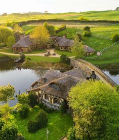 an aerial view of a house with thatched roofs next to a lake and green fields