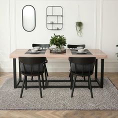 a dining table with black chairs and a plant in the center is surrounded by white walls