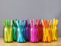 there are many different colored cups with straws in them on the table next to each other