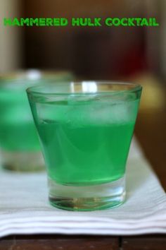 two glasses filled with green liquid sitting on top of a table