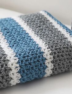 a blue and white crocheted blanket laying on top of a pillow