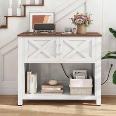 a white table with books and a radio on it next to some stairs in a house