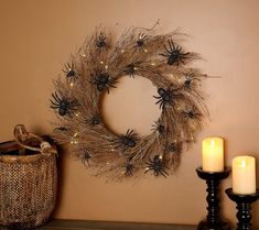 a wreath with spider webs on it next to two candles