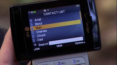 a person holding a cell phone in their hand with the screen showing contact list on it