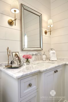 a white bathroom with marble counter tops and gold fixtures