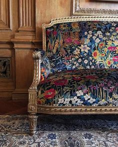 an ornately decorated couch sitting in front of a wooden paneled wall and floor