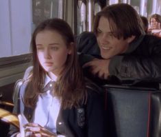 a man and woman sitting on a bus looking at their cell phones in front of them