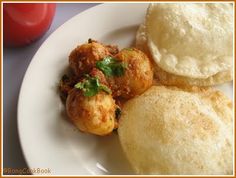 some food is on a white plate and next to a red pepper shaker with a tomato in the background