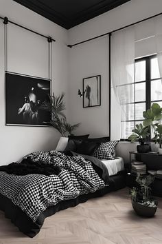 a bedroom with black and white bedding, potted plants and pictures on the wall