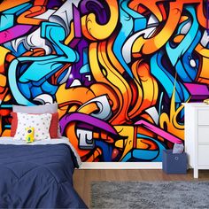 a bed room with a neatly made bed next to a wall covered in colorful graffiti