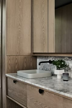 a kitchen with wooden cabinets and marble counter tops, including a sink in the center