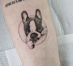 a small black and white dog tattoo on the leg