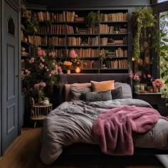 a bed sitting in front of a window filled with lots of flowers and bookshelves