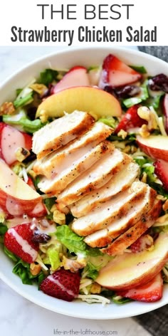 the best strawberry chicken salad is in a white bowl with strawberries, apples and lettuce