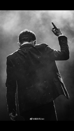 a man in a suit is holding his cell phone up to the side while standing on stage