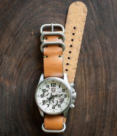 After years of creating leather watch straps for ourselves for use on a variety of watches, we are excited to release our version of the simple NATO leather strap. The NATO strap has an iconic history for a range of vintage military issued watches. We've tested this strap on a variety of watches, from Tudor to Rolex and Timex to Luminox. It's a beautiful addition to new and vintage watches. Three widths available: 18mm, 20mm, and 22mm All straps are precisely cut from 4 ounce bridle leather and Luxury Leather Watch Strap, Coconut Lane Watch Straps, Luxury Vintage Watch Strap, Canvas Strap Watch, Nato Watch Strap, Brown Apple, Nato Strap Watches, Rolex Explorer, Black Apple