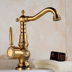 a gold faucet sitting on top of a bathroom sink next to a white towel