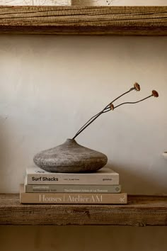 two books stacked on top of each other next to a vase with flowers in it