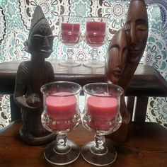 two wine glasses sitting on top of a wooden table next to a buddha figurine