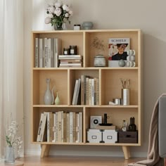 a bookshelf filled with lots of books next to a chair and vases