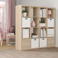 a living room with a book shelf filled with lots of books and boxes on top of it