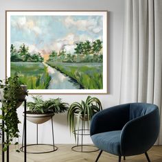 a painting hanging on the wall next to two chairs and a potted plant in front of it