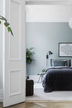 a bed sitting in a bedroom next to a green plant on top of a wooden floor