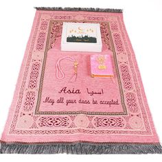 a pink rug with writing on it and other items sitting on top of the rug