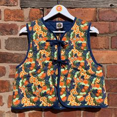 a vest hanging on a brick wall with an orange and blue flowered pattern,