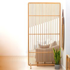 a living room with a plant in the corner and a wooden cage on the wall