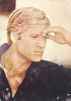 a man with blonde hair is holding his hand to his head