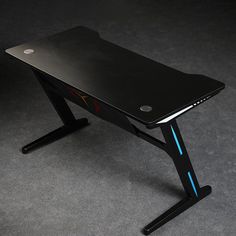 a desk with a laptop on it is shown in this close up photo, the table has a black surface and blue lines running along the edge