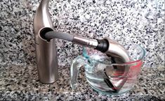 a glass bowl with a metal faucet next to it on a granite counter top