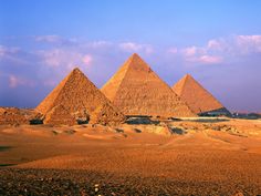 three pyramids in the desert under a blue sky