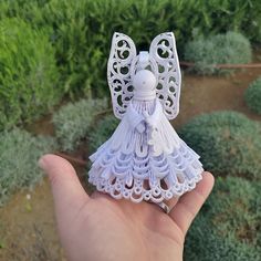 a hand holding a small white angel ornament