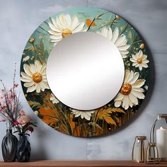 a mirror with flowers painted on it sitting next to a vase and some other items