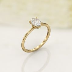 a yellow gold engagement ring with a single diamond in the center, on a white surface